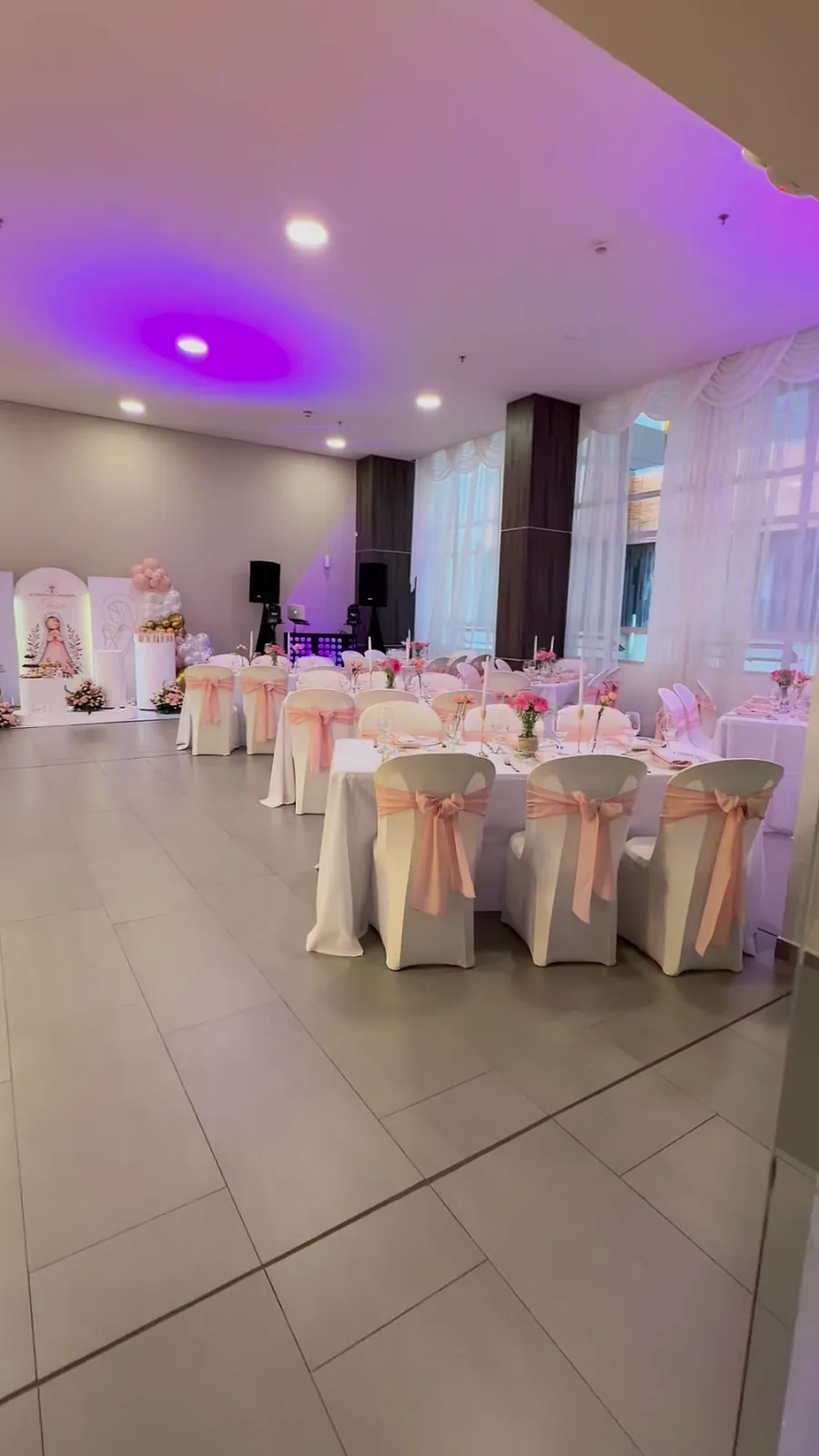 Salón con mesas y sillas vestidas con lazos rosados